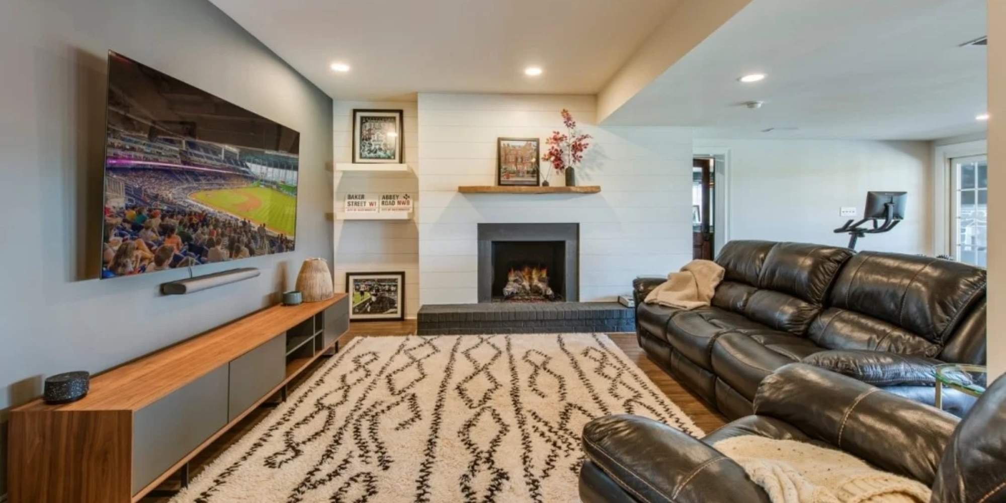 Modern living room with built-in shelves, black brick fireplace, and large screen TV