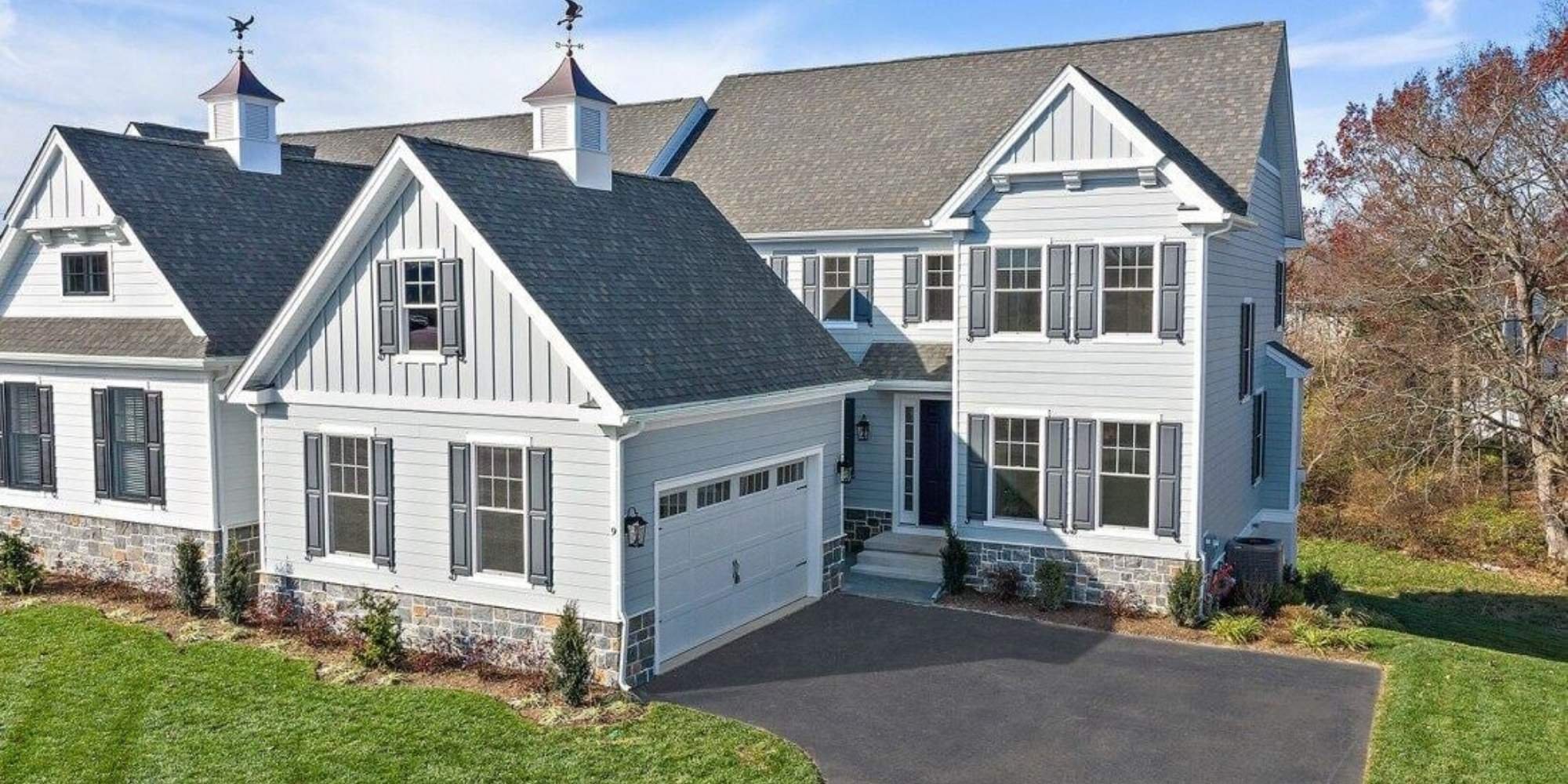 Custom-built white farmhouse-style home with stone accents and dark shutters in West Chester by Thompson Communities