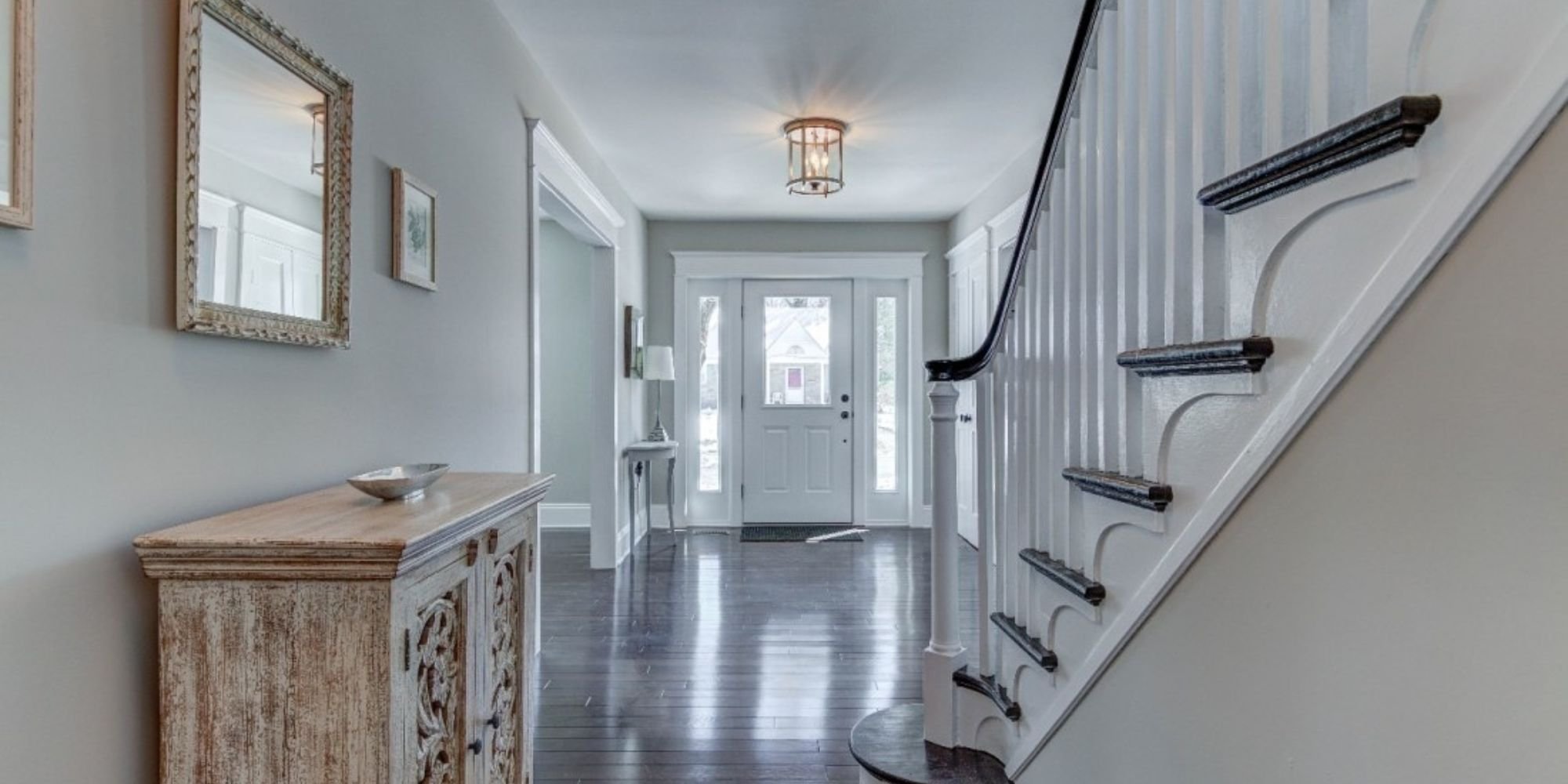 Bright and welcoming foyer with a curved staircase and modern lighting, Thompson Communities remodel, West Chester, PA