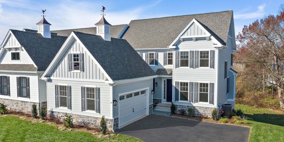 Custom home in Chester County, PA by Thompson Communities with white siding, shutters, and attached garage