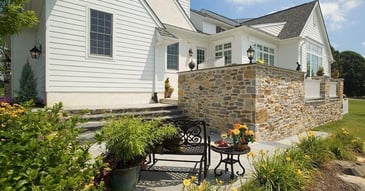Bright white custom home with traditional architecture and natural stone terrace by Thompson Communities