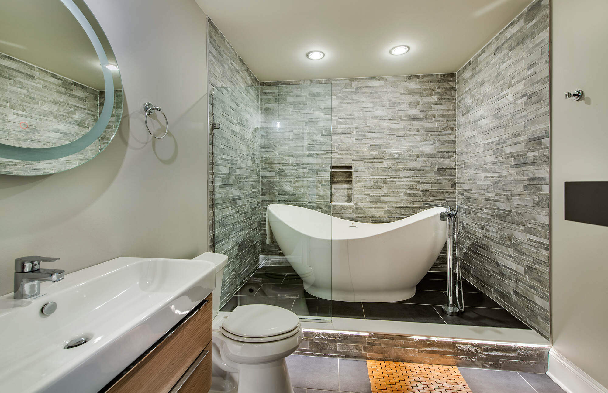 Luxurious spa-style bathroom with a freestanding tub and stone tile walls, Thompson Communities remodel, West Chester, PA