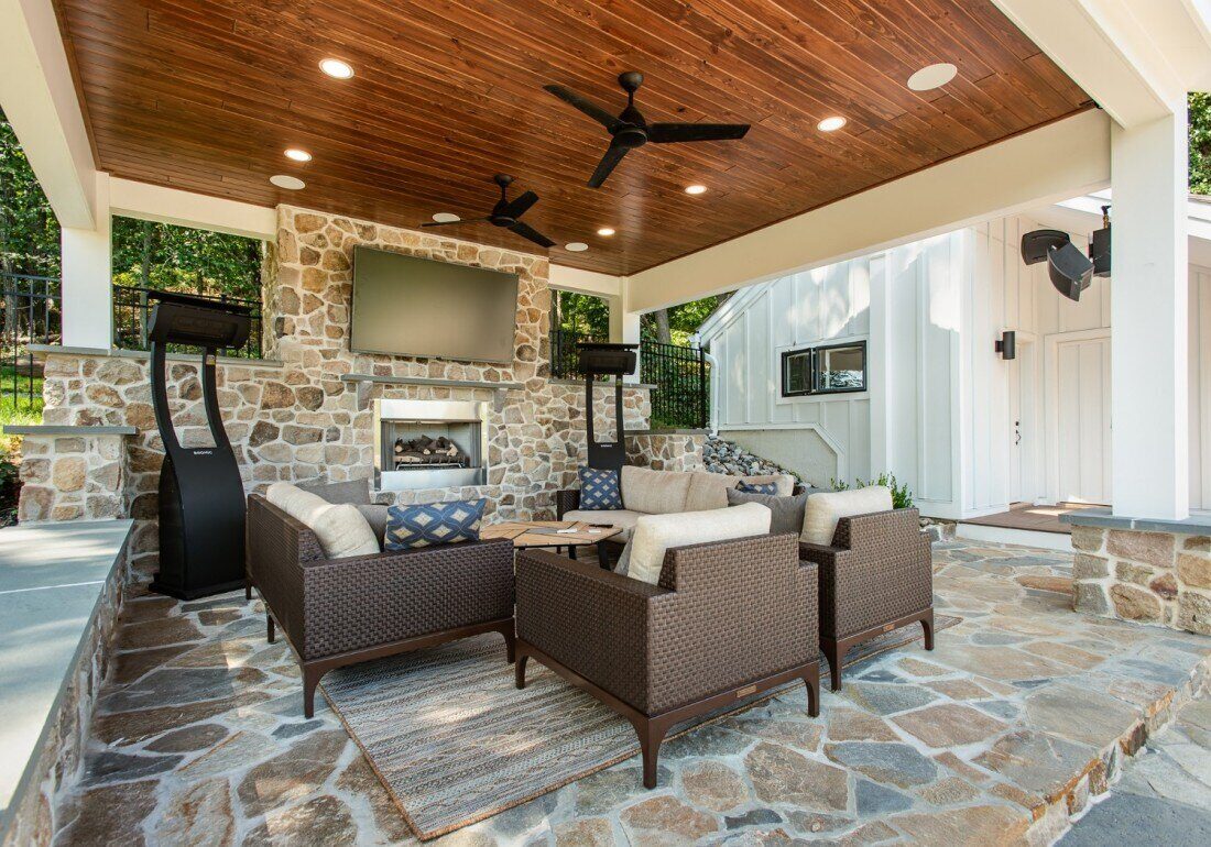 Covered outdoor lounge area with a stone fireplace in a Thompson Communities home addition, West Chester, PA
