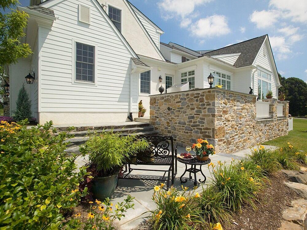 Side patio with stonework and flowers in a West Chester, PA home addition by Thompson Communities