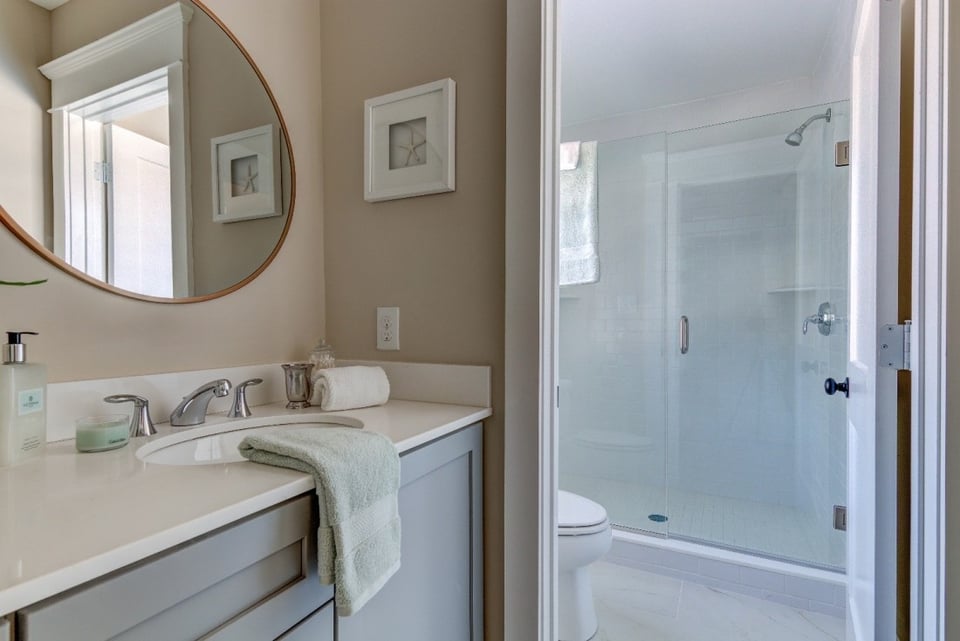 Contemporary bathroom with large mirrors and dark wood cabinetry, part of a West Chester, PA remodel by Thompson Communities - How Much Does It Cost to Remodel a Bathroom in the Tri-State Area