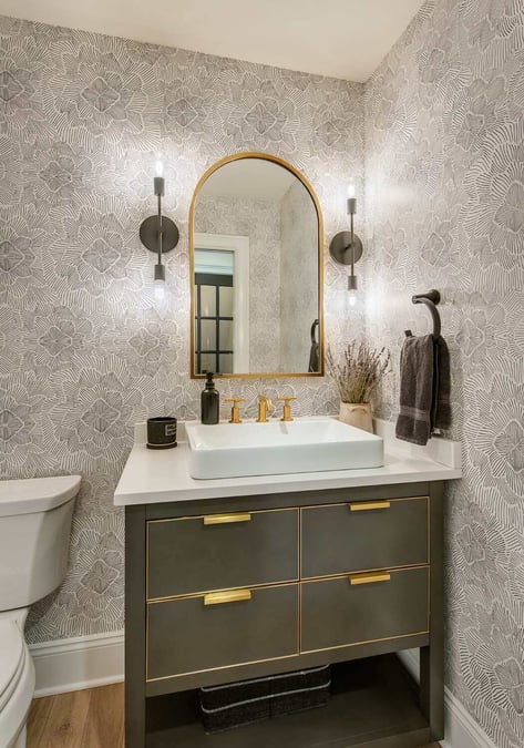 Elegant powder room with gold fixtures and floral wallpaper, part of a bathroom remodel by Thompson Communities in West Chester, PA