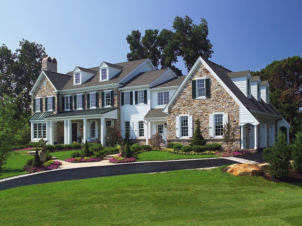 Front view of a Thompson Communities custom home in West Chester, PA, with beautiful stonework and vibrant greenery Front view of a Thompson Communities custom home in West Chester, PA, with beautiful stonework and vibrant greenery