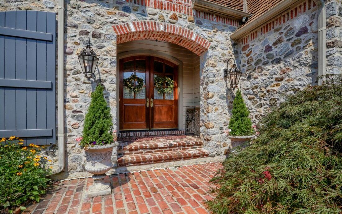 Shrubbery surrounding red brick entrance to double front door - West Chester, PA custom home construction cost - Thompson Communities