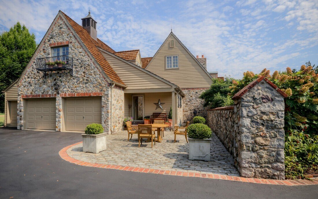 Exterior view of a custom home built by Thompson Communities in West Chester, PA, featuring a stone façade and three-car garage
