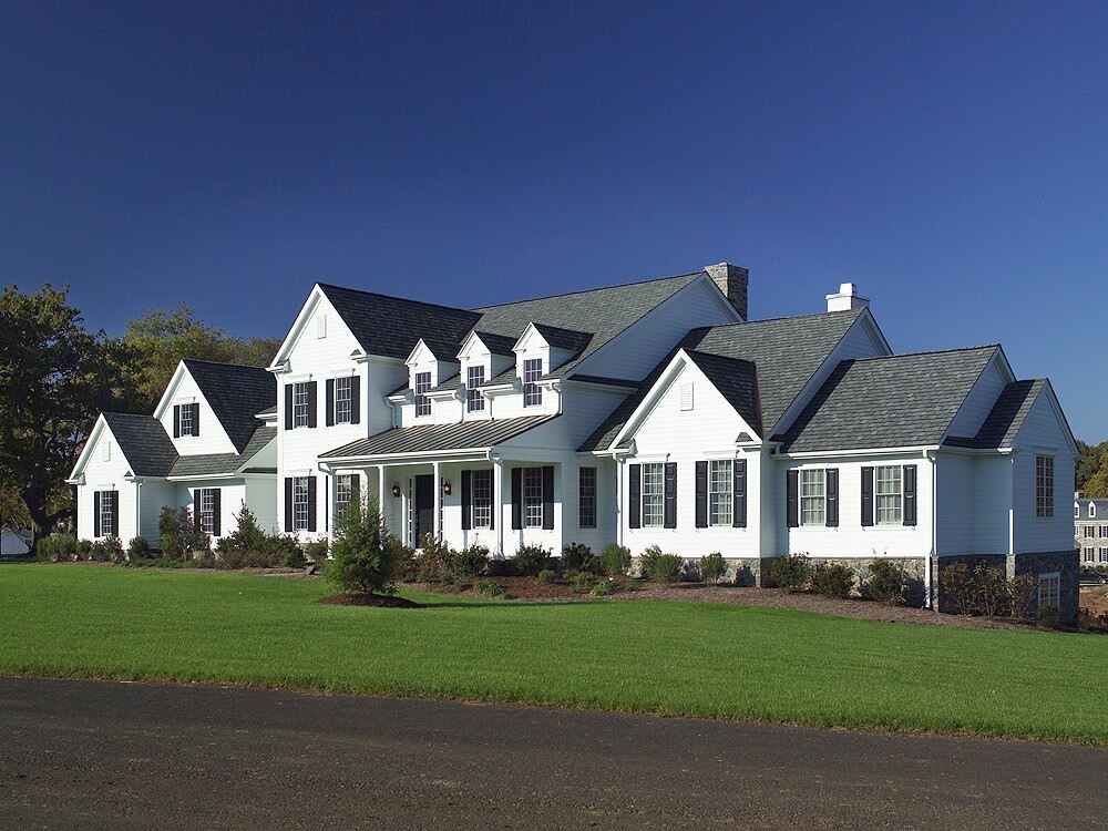 Spacious white custom home by Thompson Communities in West Chester, PA, featuring gabled roofs and lush green lawn