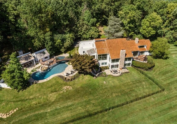 Aerial view of a luxurious property with a pool and spacious lawn, remodeled by Thompson Communities, West Chester, PA