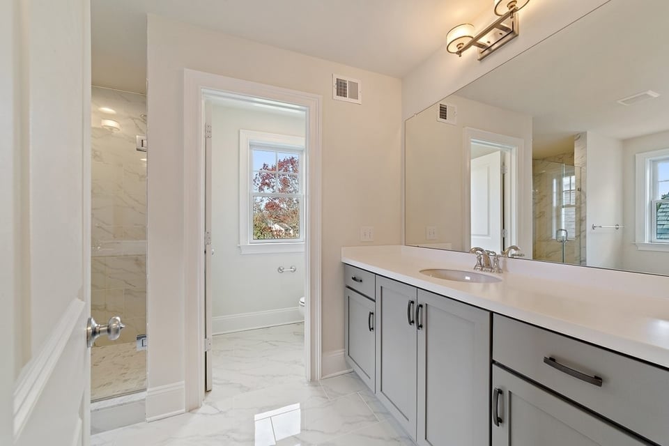 Bright guest bathroom with white cabinets and large mirrors, remodeled by Thompson Communities, West Chester, PA - How Much Does It Cost to Remodel a Bathroom in the Tri-State Area