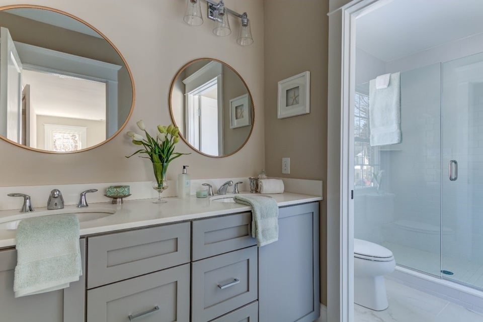 Elegant double vanity bathroom with round mirrors and modern fixtures, remodeled by Thompson Communities, West Chester, PA - How Much Does It Cost to Remodel a Bathroom in the Tri-State Area