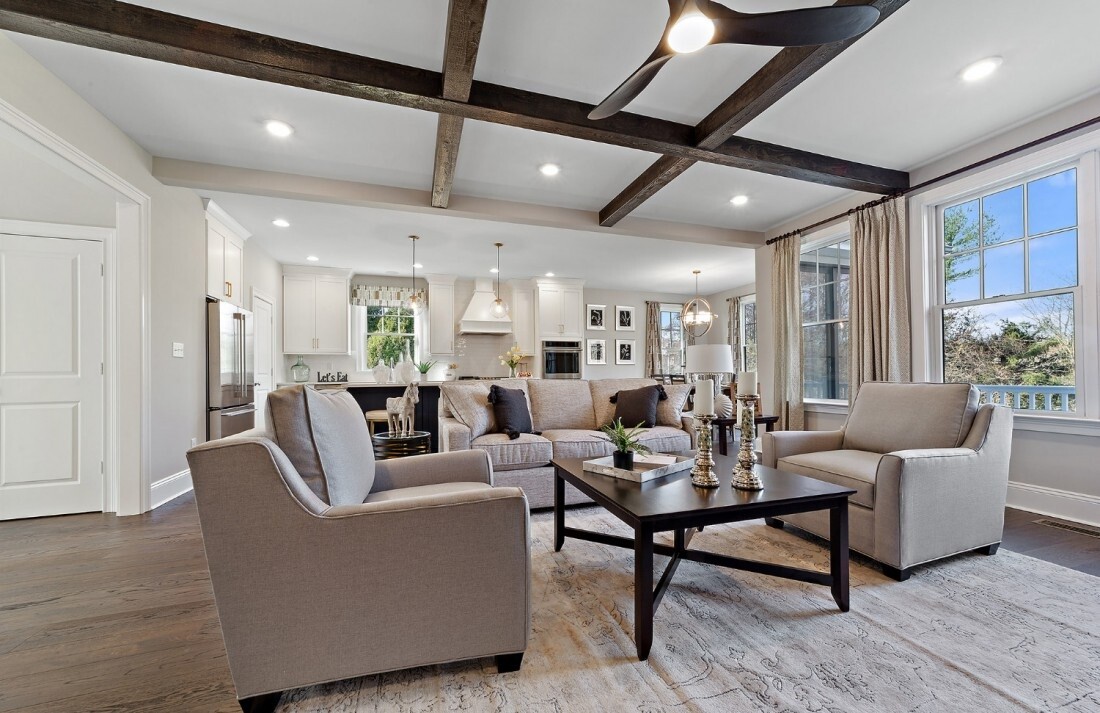 Open-concept living room with exposed wood beams and modern furniture, Thompson Communities remodel, West Chester, PA