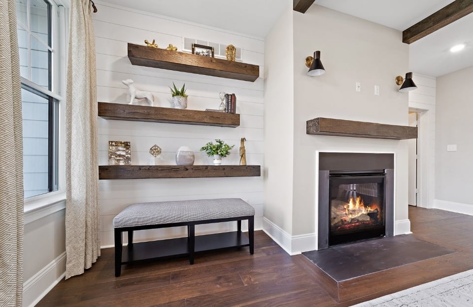 Front room with a fireplace and thick wood shelving featuring a grey bench - West Chester PA | Thompson Communities