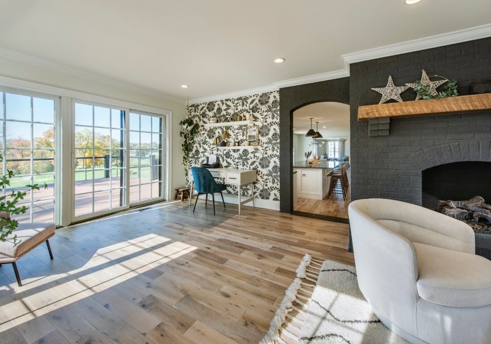 Modern living space with large sliding glass door, custom black fireplace, and open view into a designer kitchen - Thompson Communities - Chester County Builder and Remodeler - Home remodeling process and timeline