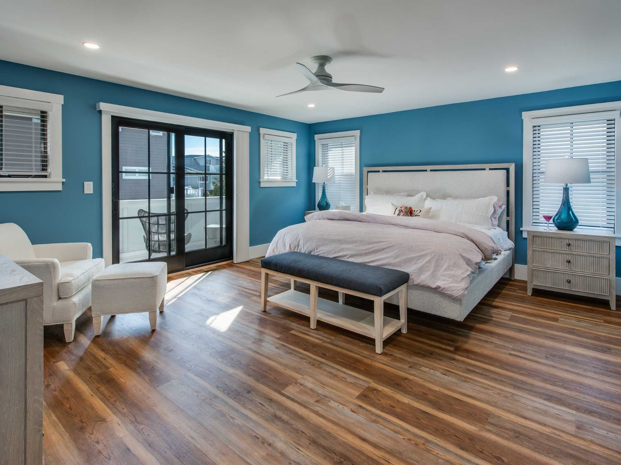A large bedroom with blue walls and French doors that open onto a private balcony by Thompson Communities in Avalon A large bedroom with blue walls and French doors that open onto a private balcony by Thompson Communities in Avalon