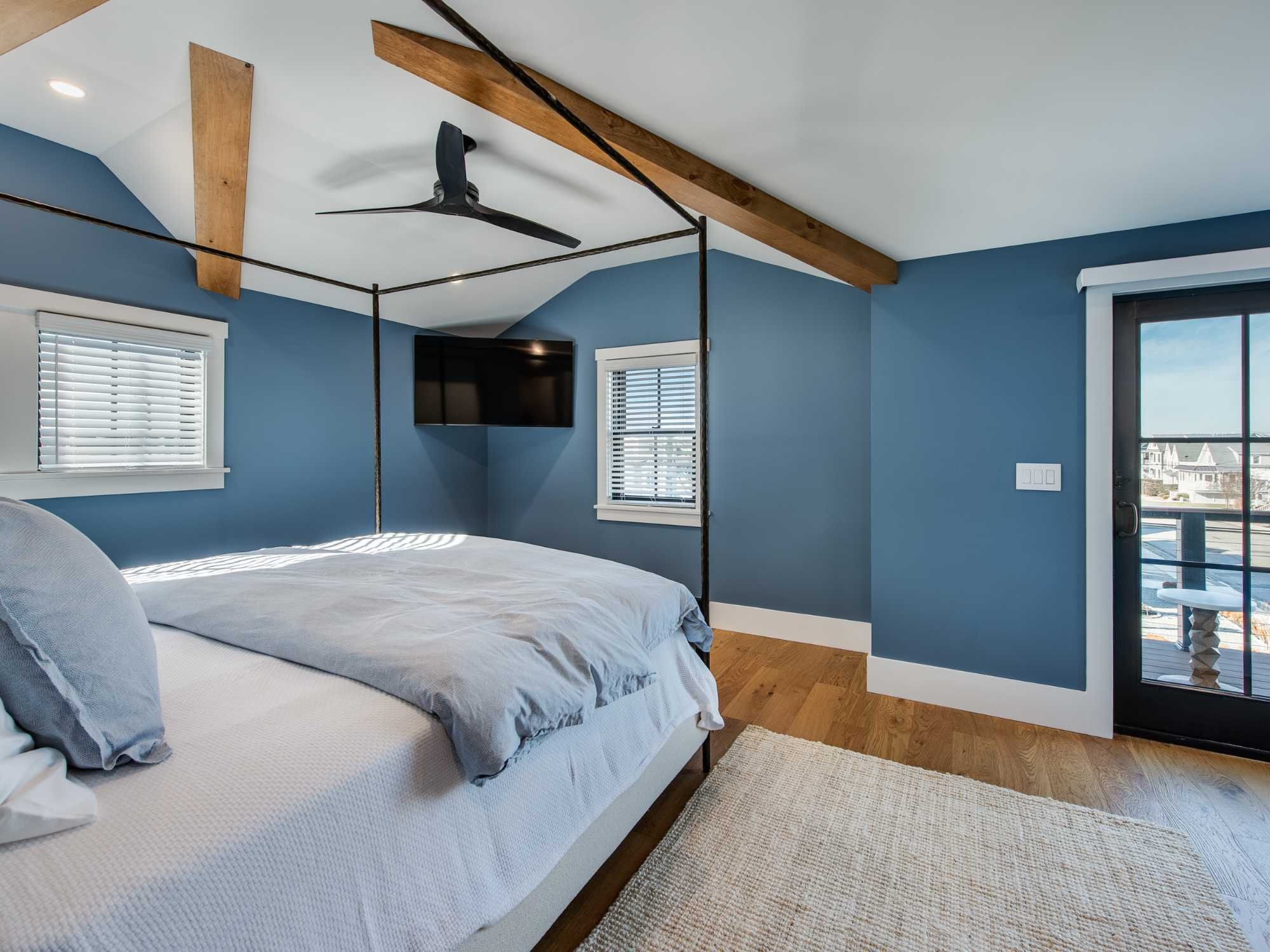 Primary bedroom in a custom home with blue walls, white trim, and exposed beams by Thompson Communities in Avalon Primary bedroom in a custom home with blue walls, white trim, and exposed beams by Thompson Communities in Avalon