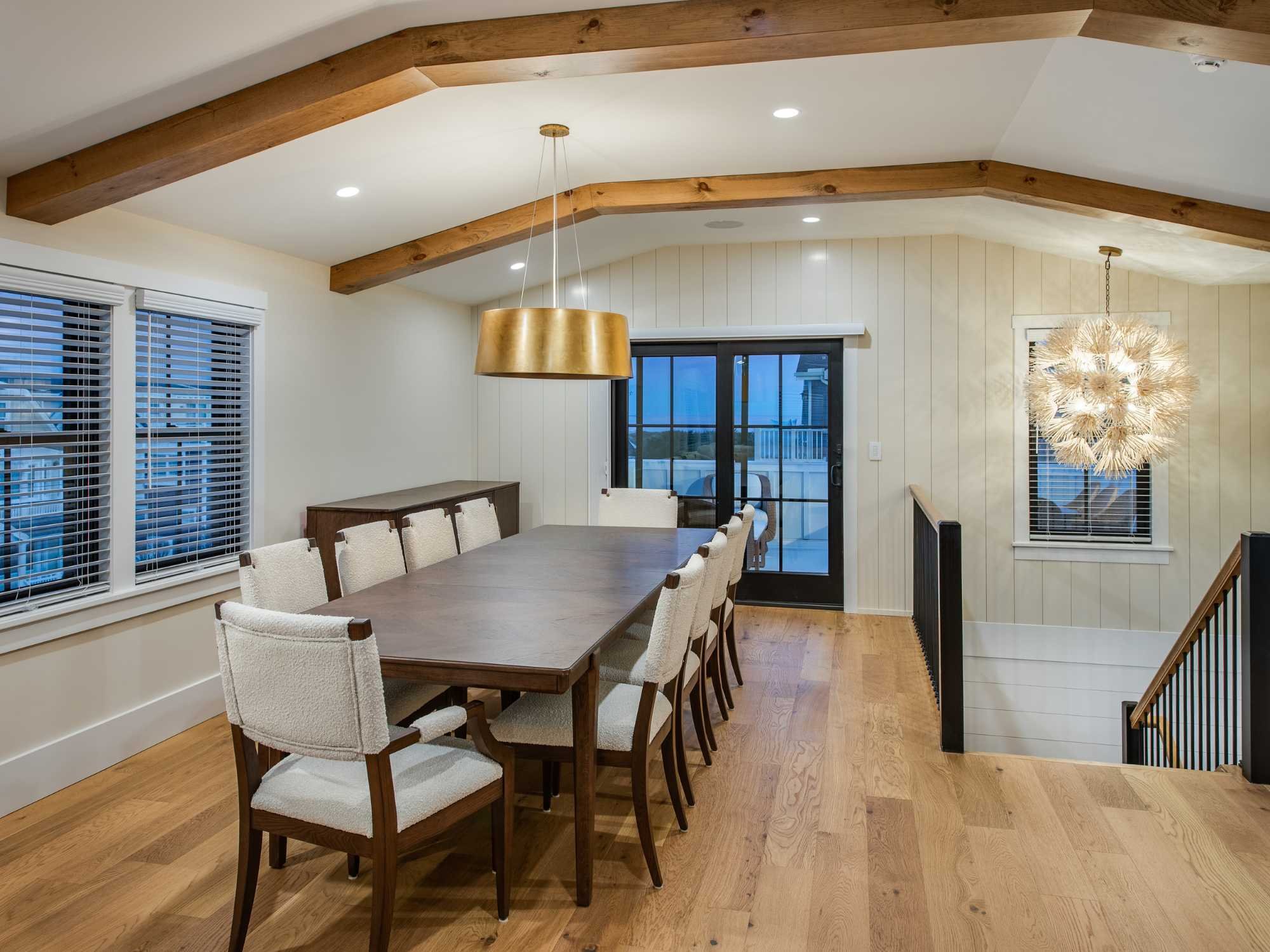 Open dining area in a custom home with exposed beams and custom lighting by Thompson Communities in Avalon