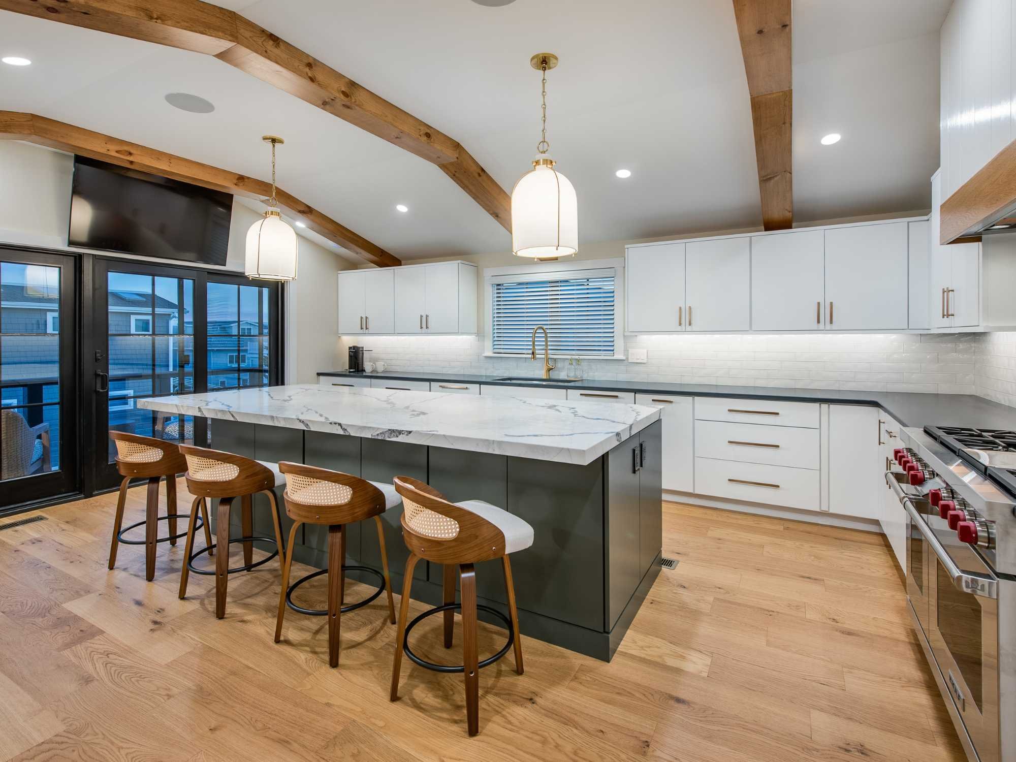 An open-concept kitchen in a custom home with high ceilings, exposed beams, and a large island with seating by Thompson Communities in Avalon An open-concept kitchen in a custom home with high ceilings, exposed beams, and a large island with seating by Thompson Communities in Avalon