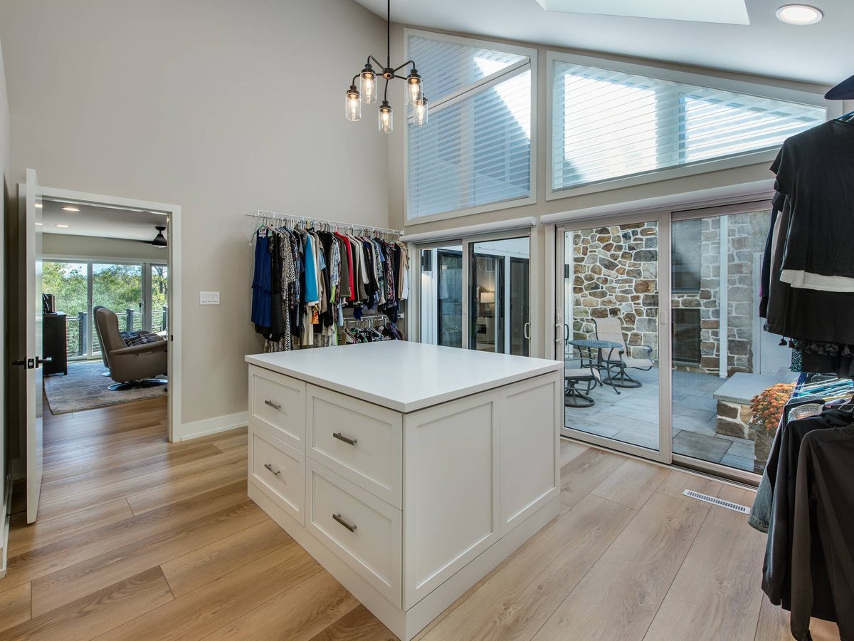Custom walk-in closet with a center island, open clothing racks, skylights, and a courtyard view