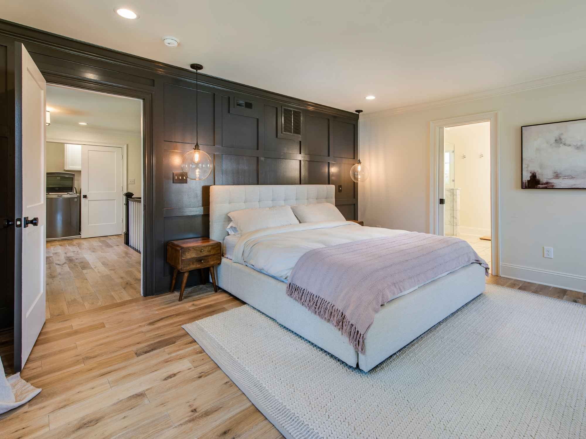 Modern primary bedroom with a dark accent wall and soft lighting in a whole  home remodel by Thompson Communities in West Chester, PA