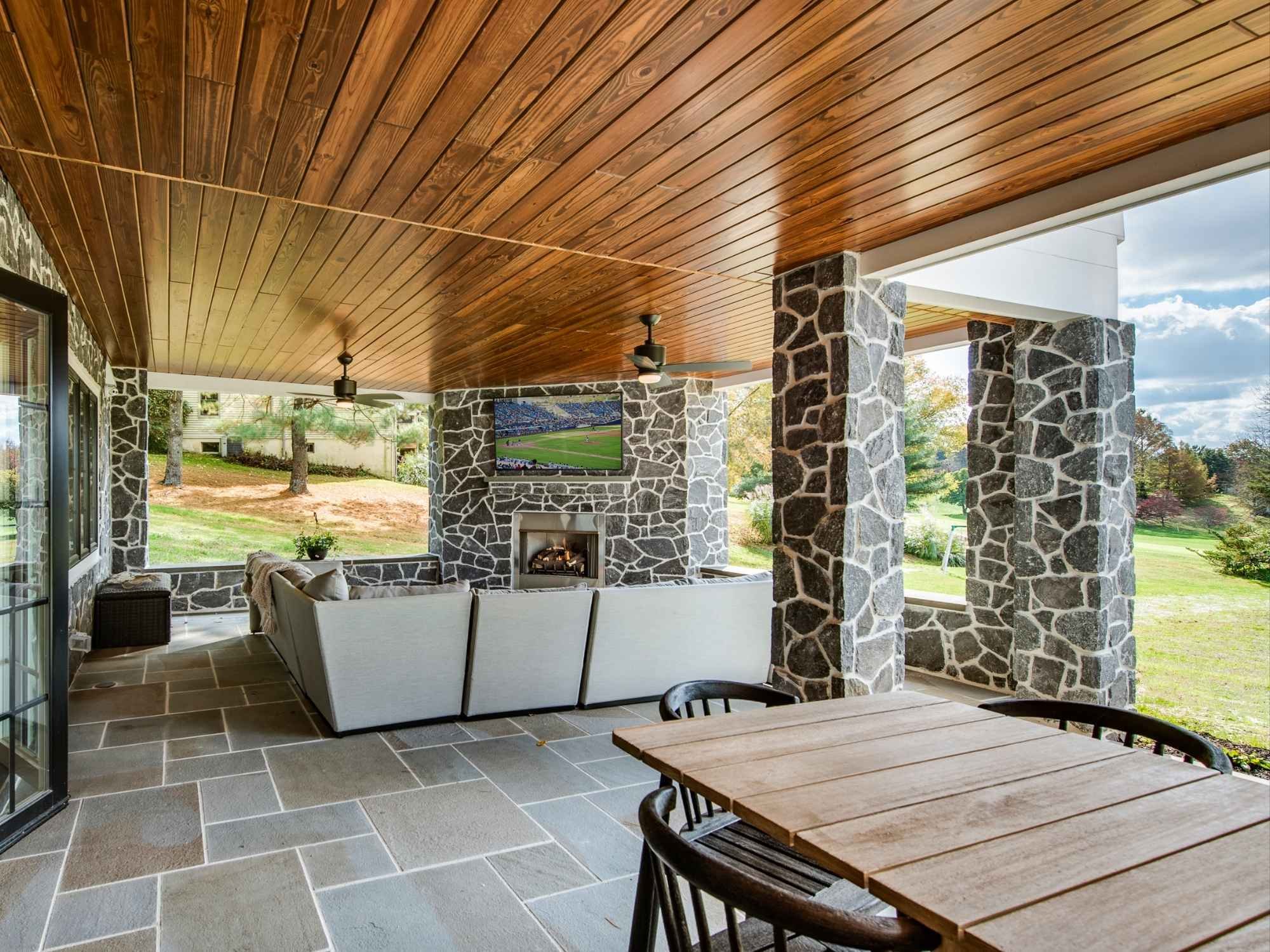Stylish covered patio with rustic stone and wood elements in West Chester whole home remodel by Thompson Communities