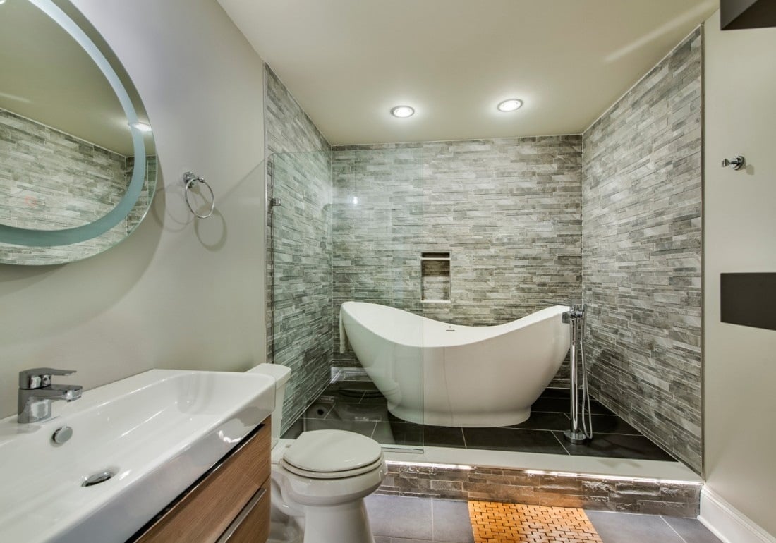 Modern bathroom with freestanding white tub and stone accent wall, remodeled by Thompson Communities in West Chester, PA